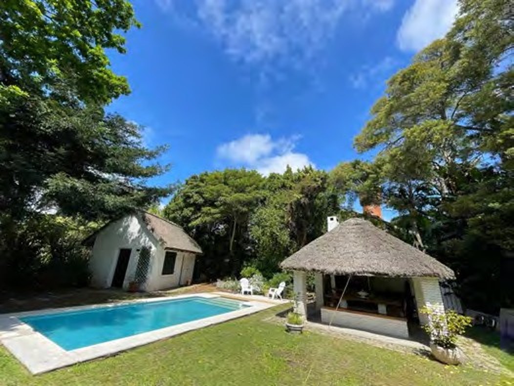 Swimming pool, lawn and thatched quincho in the garden